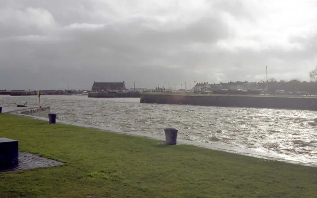Boats and waterfront buildings at Galway Harbour under a cloudy sky